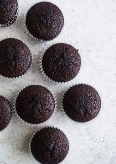 six chocolate cupcakes sitting on top of a white countertop next to each other