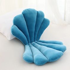 a blue shell shaped pillow sitting on top of a bed