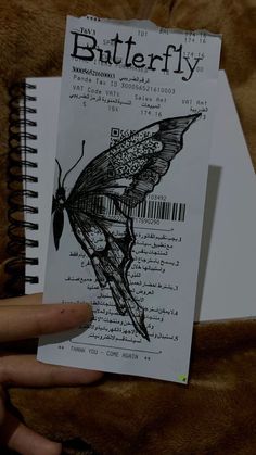 a hand holding a piece of paper with a butterfly on it's back side