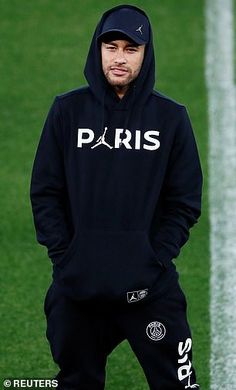 a man standing on top of a soccer field wearing a black hoodie and sweatpants