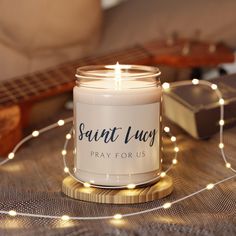 a white candle sitting on top of a wooden table next to a string of lights