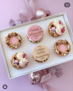 pink and gold decorated cupcakes in a box