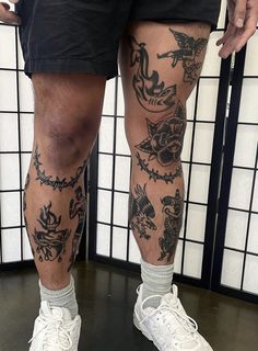 a man with tattoos on his legs standing in front of a tiled wall