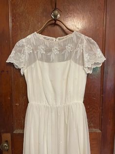 Simply gorgeous white sheer dress with embroidery throughout. Capped sleeves, full skirt. Fully lined. Probably from the 70s or 80s, but 50s style. No tags remain.  Material and size unknown. belt missing. Perfect party dress or wedding dress.  Center zipper and eye closure in the back.  Shoulder 14" Bust 17" Waist 12.5" no stretch Hips up to 20" Length to waist from shoulder 17" Length from waist to hem 35" Arm scythe 6" Total length at 51" Wedding Dress Embroidered, White Sheer Dress, Vintage 70s Dress, Vintage Dress 70s, 50s Style, 70s Dress, 50s Fashion, Sheer Dress, Dress Wedding