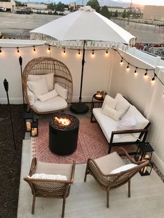 an outdoor patio with wicker furniture and string lights on the ceiling, along with a fire pit