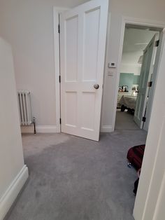 an open door in a white room next to a luggage bag and radiator