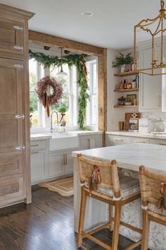 a kitchen with white cabinets and wooden floors, two bar stools in front of the counter