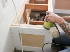 a man using a sander on the side of a cabinet