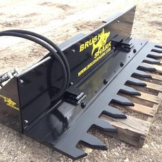 a black snow plow sitting on top of a dirt field