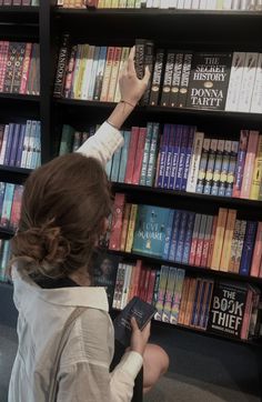 a girl sitting in front of a bookshelf in a bookstore and holding “the secret history“ by Donna Tartt Book Store Owner Aesthetic, Bookstore Worker Aesthetic, Bookstore Girl Aesthetic, Book Shopping Aesthetic, Worm Aesthetic, Cooper Aesthetic, Buying Books, Reader Aesthetic, Joy Williams