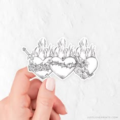 a hand holding a sticker with two hearts and roses on fire in the background