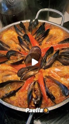 a large pan filled with mussels and sauce on top of a stovetop