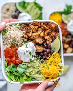 a person holding up a bowl filled with different types of salads and rice in it