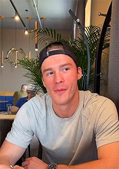 a man sitting at a table with a plate of food in front of him and another person behind him