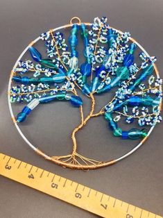 a blue and white tree of life brooch sitting next to a measuring ruler on a table