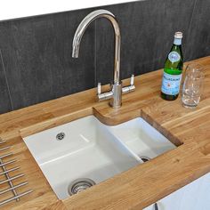 a white sink sitting under a kitchen faucet next to a wooden counter top