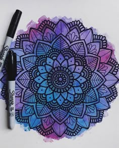 a drawing of a blue and purple flower with black marker on paper next to it