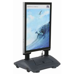 a computer monitor sitting on top of a stand with an ocean wave in the background