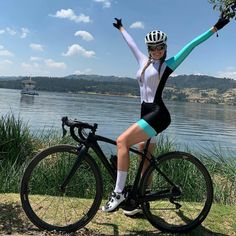 a woman is posing on her bike by the water