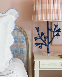 a bedroom with pink walls and a blue tree lamp on the nightstand next to it