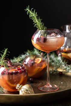 two glasses filled with liquid sitting on top of a table next to christmas decorations and greenery