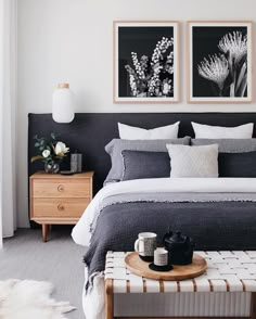 a bed with two pictures above it and a tray on the end table in front of it