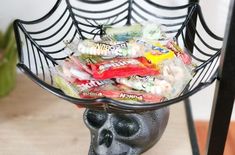 a skull with candy in it's mouth sitting on a table next to a spider web