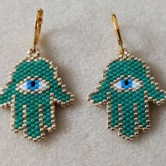 two green hamsa earrings with blue eyes