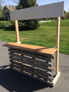 a wooden bench sitting on the side of a road next to a grass covered field