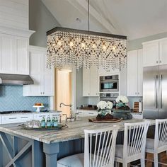 a kitchen with white cabinets and blue island