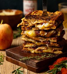 a stack of pancakes sitting on top of a wooden cutting board next to an apple