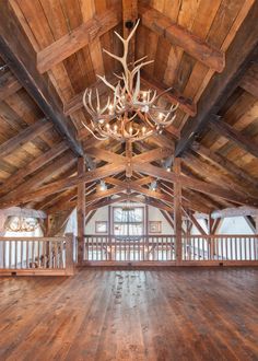 an empty room with wood floors and beams on the ceiling is lit by a chandelier