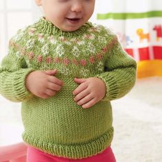 a small child wearing a green sweater and pink pants