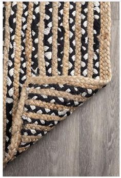 black and white rug with braided edges on wooden floor, closeup view from above