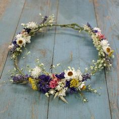 a flower crown is sitting on a wooden floor with white, purple and yellow flowers