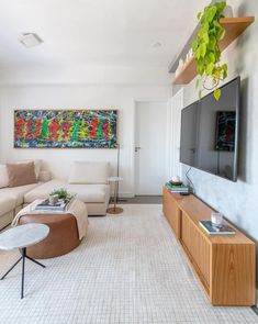 a living room filled with furniture and a flat screen tv mounted on a wall above a wooden entertainment center