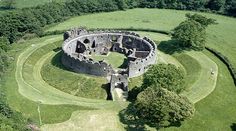 an aerial view of a castle in the middle of a green field with trees around it