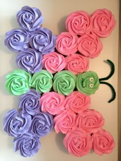 the wall is decorated with pink, purple and green cupcakes that are shaped like flowers