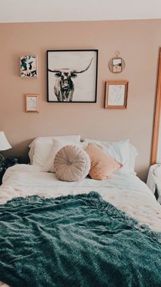 a bed with blankets, pillows and pictures on the wall above it in a bedroom