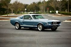 a blue mustang sitting in the middle of a parking lot