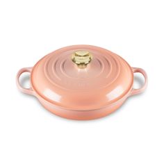 a pink casserole dish with gold handles and an open lid on a white background