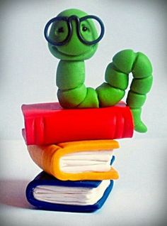 a green worm sitting on top of a stack of books