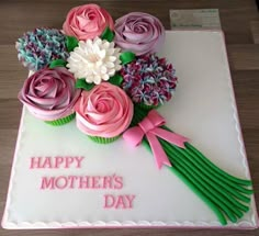 a birthday cake decorated with pink and purple flowers on top of a white sheet that says happy mother's day