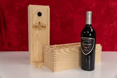 a bottle of red wine next to a wooden box with a corkscrew in it