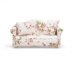 a white couch with pink and green flowers on the back, sitting in front of a white background