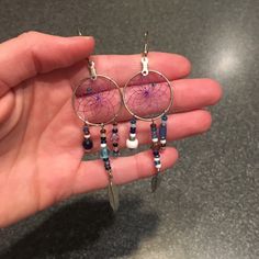 a person is holding some kind of earrings in their hand and it has beads hanging from the hoop