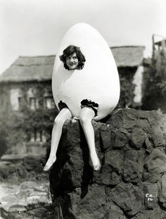 a woman sitting on top of a rock with an egg in the shape of a person