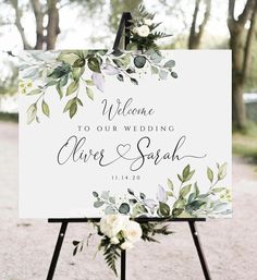 a welcome sign with greenery and white flowers