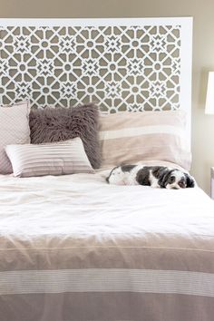 a black and white dog laying on top of a bed next to two lamps in a bedroom