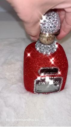 someone is opening the top of a red bottle with silver sparkles on it,